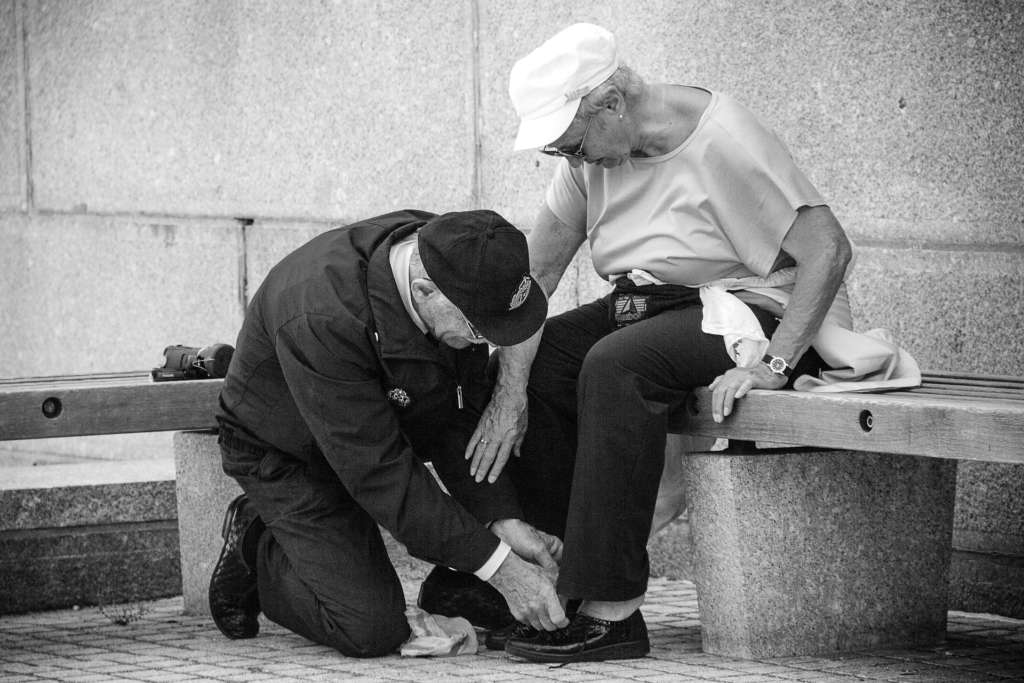 Man looking tying woman's shoelace