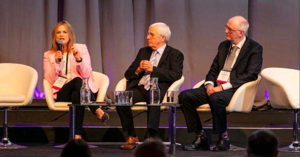 woman and 2 men on stage talking