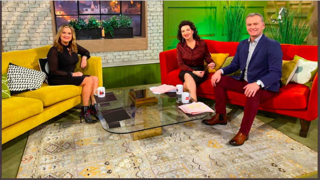photo of woman on sofa in TV studio with a man and a woman on another sofa
